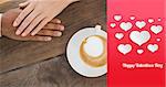 Couple holding hands beside cappuccino against happy valentines day