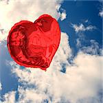 Red heart balloon against bright blue sky with clouds