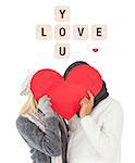 Couple in winter fashion posing with heart shape against love you tiles