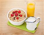 Healty breakfast with muesli, berries, milk and orange juice on wooden table