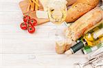 White wine, cheese and bread on white wooden table background with copy space