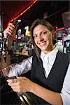 Happy barmaid pulling a pint of beer in a bar