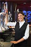 Happy barmaid pulling a pint of beer in a bar