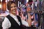 Happy barmaid smiling at camera in a bar