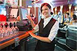 Happy barmaid using touchscreen till in a bar