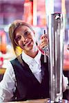 Pretty barmaid pulling pint of beer in a bar