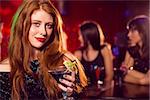 Pretty redhead drinking a cocktail at the nightclub