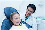 Female dentist examining girls teeth in the dentists chair