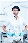 Portrait of happy confident female dentist with hands on hips