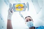 Low angle portrait of female dentist adjusting light