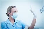 Concentrated female dentist in surgical mask holding injection