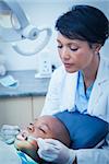 Female dentist examining boys teeth in the dentists chair