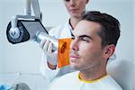 Serious young man undergoing dental checkup in the dentists chair