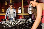 Smiling friends playing table football in a pub