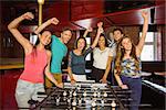 Portrait of happy friends playing table football in a pub