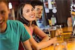 Smiling friends talking and drinking beer in a bar