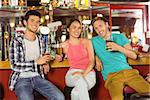 Smiling friends drinking beer together in a bar