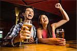 Happy friends drinking beer and cheering together in a bar