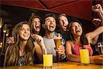 Happy friends drinking beer and cheering together in a bar