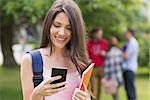 Happy student sending a text outside on campus at the university