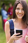 Pretty student sending a text outside on campus at the university