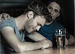 Caring friend comforting upset man in a bar