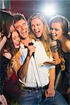 Happy friends singing karaoke together in a bar