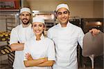Team of bakers smiling at camera in a commercial kitchen