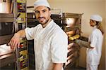 Handsome baker smiling at camera in a commercial kitchen