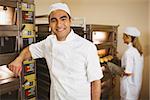 Handsome baker smiling at camera in a commercial kitchen