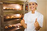 Baker smiling at camera beside oven in a commercial kitchen