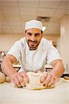 Baker kneading dough at a counter in a commercial kitchen