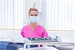 Dentist in mask wearing pink scrubs and looking at camera at the dental clinic