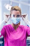 Dentist in pink scrubs looking at camera in mask and gloves at the dental clinic