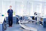 Dentist in blue scrubs standing beside chair at the dental clinic