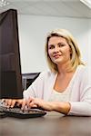 Mature student using laptop looking at camera in the office