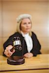 Serious judge with a gavel wearing robes and wig in the court room