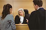 Judge wearing dress and wig listening lawyers in the court room