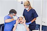 Dentist doing injection and patient protesting in dental clinic