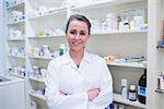 Portrait of a smiling student in lab coat with arms crossed in the pharmacy