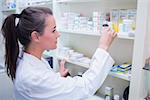 Smiling student taking jar from shelf in the pharmacy