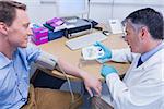 Smiling doctor measuring the blood pressure of his patient at the hospital