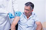 Doctor giving injection to his patient at the hospital