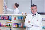 Smiling pharmacist standing with arms crossed in the pharmacy