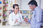 Trainee giving a bag of pills to a customer in a drugstore