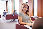 Happy young student sitting on couch using laptop at the university