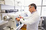 Senior pharmacist using machine to make medicine at the laboratory