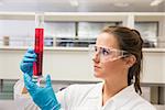 Young pharmacist holding beaker of red liquid at the laboratory