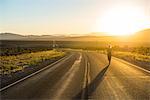 Woman walking down a long winding road at sunset in eastern Nevada, United States of America, North America