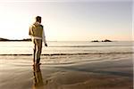 A man pauses while skipping rocks into the water at Bailey's Beach on an autumn morning, Newport, Rhode Island, USA.